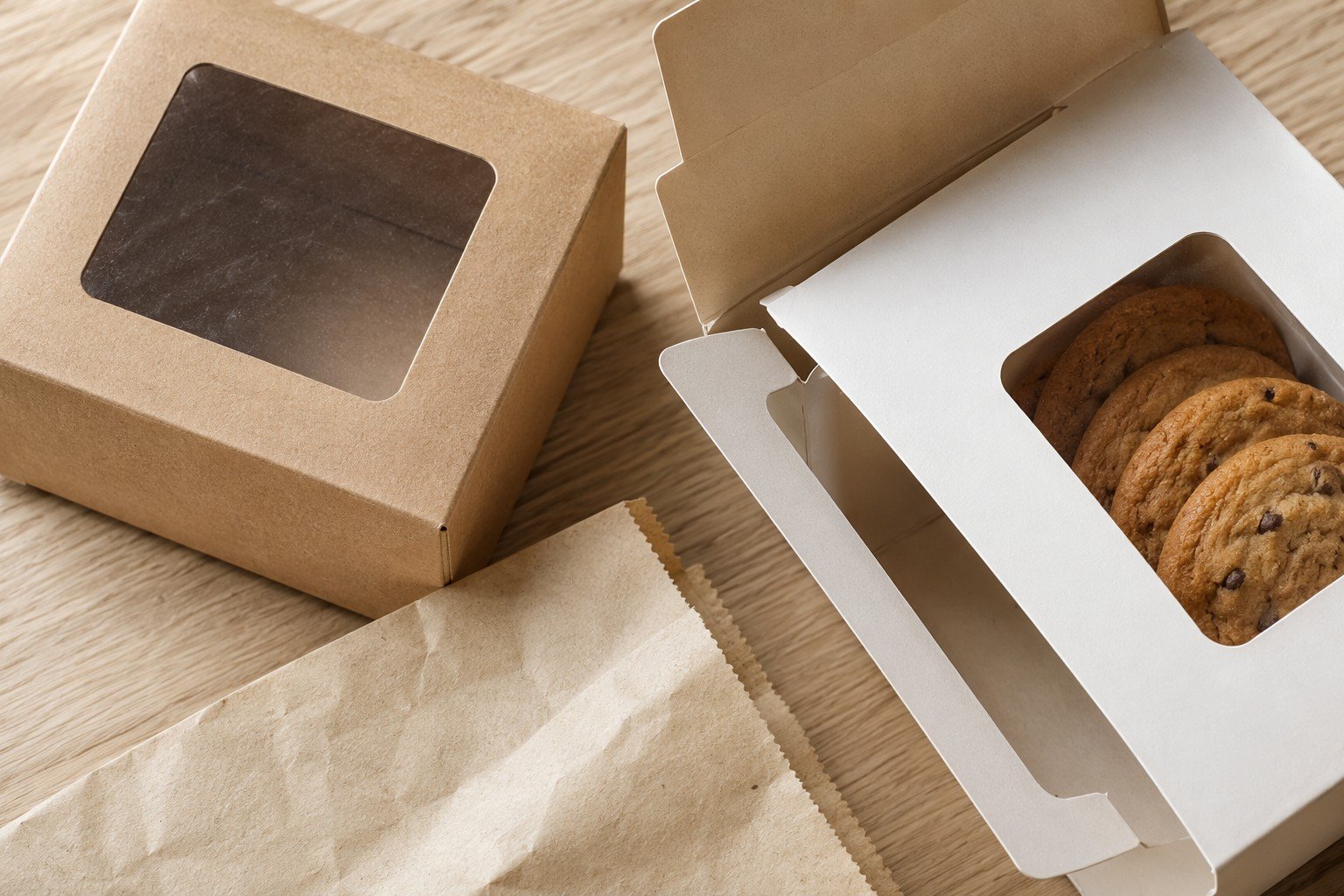 Paper packaging — close-up of kraft paperboard carton with window patch showing cookies inside for product visibility